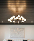 Modern interior featuring black wood ceiling and brass chandelier with white globes, creating a rustic industrial vibe.