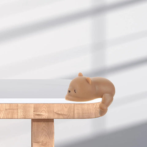 Dog and bear shaped silicone table corner protectors on a wooden table corner, anti collision corner guards for furniture safety and childproofing