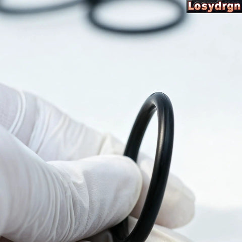Close-up of a gloved hand holding an O-ring from Two Kit Pack Radiator Hose T Pipe O Ring Set For Ford F150 5.0L Mustang.