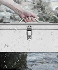 Hand holding Sturdy Portable Stainless Steel Tool Box With Metal Latch over wet rocks, showcasing water resistance