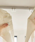 Hands holding sheer fabric curtain panels near 100 Pack Clear Plastic Roman Blind Curtain Rings Slick O Ring Clip Loops.