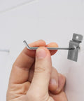 Hand holding a silver hook from the Heavy Duty Slatwall Hooks Set 50 Pieces For Phone Accessories And Retail Displays Iron Construction