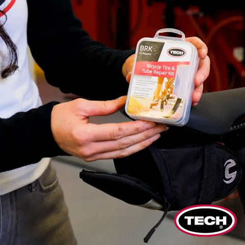 Person holding Ride Ready Bicycle Tube Patch Kit For Any Tire Inner Tube Or Tubeless Flat On The Go near bicycle saddle.