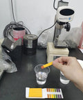 Hand using PH Test Strips 20 Pack for Urine Saliva Drinking Water Pool Spa Soap Fish Tank And Liquids with color chart in lab