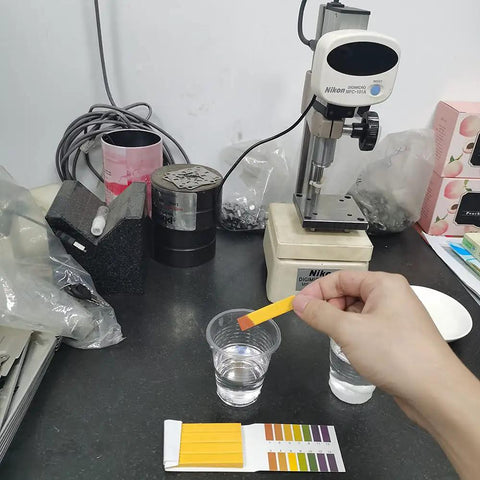 Hand using PH Test Strips 20 Pack for Urine Saliva Drinking Water Pool Spa Soap Fish Tank And Liquids with color chart in lab