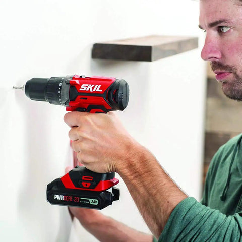 Man using 4 Tool Power Kit With 20V Cordless Drill Driver Impact Driver Reciprocating Saw And LED Spotlight Includes Two 2Ah Batteries And Charger For Home DIY Projects on wall