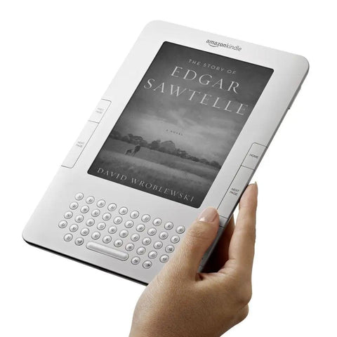 Sleek White Second Gen Ereader Features A Sharp Six Inch Screen And Free 3G Wireless To Pull Down Books Anywhere, held in hand.