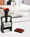 Heavy Duty Self Inking Date Stamp With Sick Brush Stroke Design And Bold Red Ink For Serious Daily Office Hustle That Built Different And Made To Last The Long Haul on a desk with a date showing.