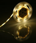 Motion Activated Bed Light With Flexible LED Strip on a reel, glowing warm soft light for bedroom nighttime navigation.