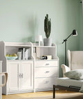 Modern living room with white cabinet, drawers, and comfortable chair, featuring a cactus plant and books.