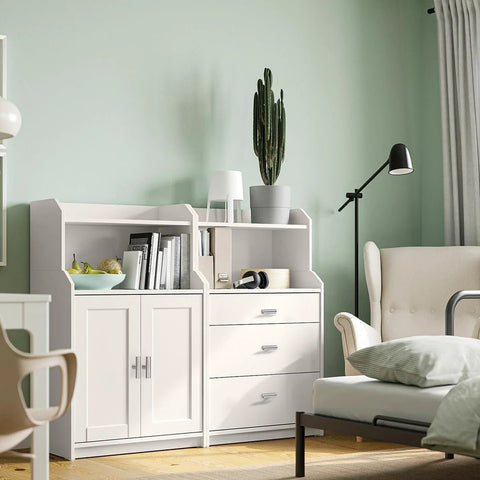 Modern living room with white cabinet, drawers, and comfortable chair, featuring a cactus plant and books.