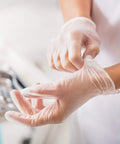 Person wearing Straight Up Premium Clear Vinyl Exam Gloves Large preparing for use in a clinic, showcasing tactile feedback.