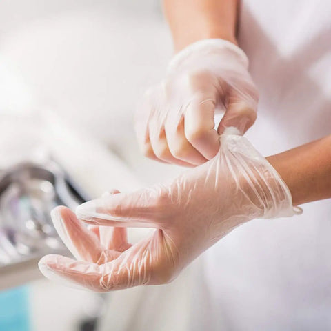 Person wearing Straight Up Premium Clear Vinyl Exam Gloves Large preparing for use in a clinic, showcasing tactile feedback.