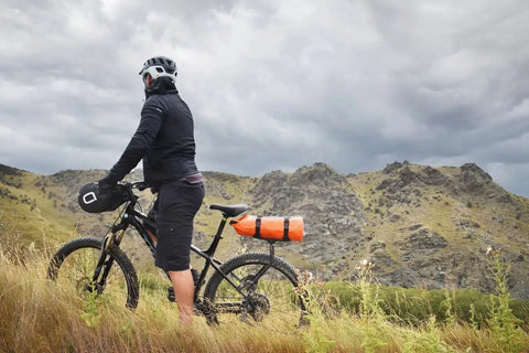 Cyclist with Spider Rear Rack And Bar Cradle For MTB And eMTB Quick Release Bike Rack System, carrying gear in mountainous terrain
