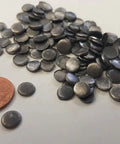 Top Shelf Nine Nine Point Nine Pure Lead Plugs And Discs For Screw Penetrations On Radiation Shielding Walls And Sound Deadening Builds Five Sixteenths Inch Diameter By Eighth Inch Thick 100 Piece Pack with a penny for size comparison.