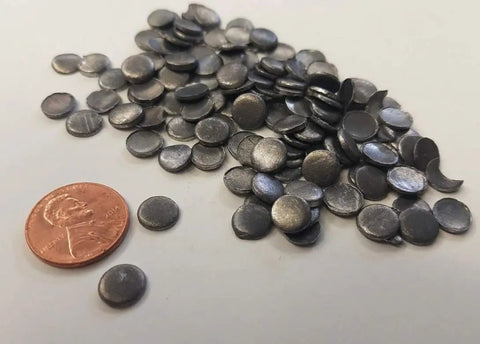 Top Shelf Nine Nine Point Nine Pure Lead Plugs And Discs For Screw Penetrations On Radiation Shielding Walls And Sound Deadening Builds Five Sixteenths Inch Diameter By Eighth Inch Thick 100 Piece Pack with a penny for size comparison.