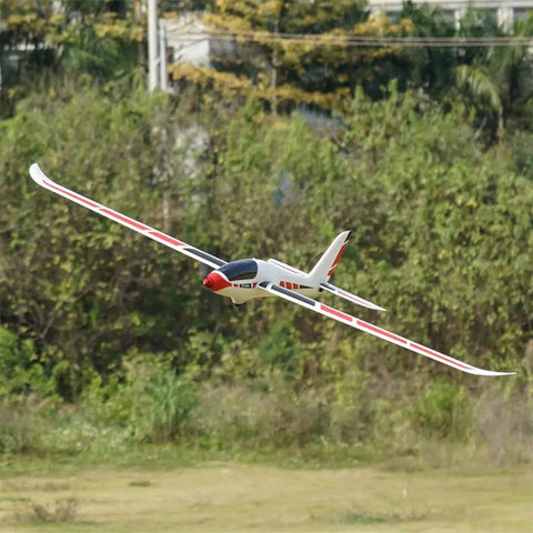 Swift 2100 RC Glider For Beginners in flight, white with red accents, 82.7 inch wingspan, showing folding prop and carbon fiber elements.