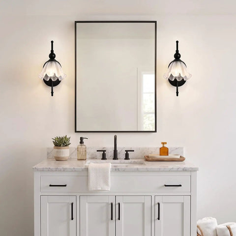 PUMING Black Wall Sconces Set of Two illuminating a modern bathroom with flower glass shades, mounted beside a mirror.