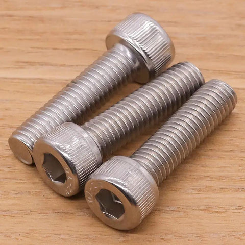 Three Premium Grade M3 X 16mm Socket Head Cap Screws, 18 8 Stainless Steel fasteners on wooden surface.
