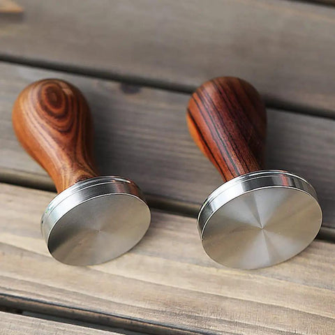 Two 51mm espresso tampers with wooden handles and stainless steel bases for stable tamping on wood surface.