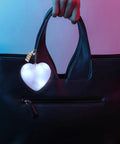 Heart-shaped purse light with sensor illuminator hanging on a black handbag using two pack heart shape purse lights with sensor.