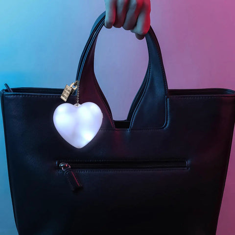 Heart-shaped purse light with sensor illuminator hanging on a black handbag using two pack heart shape purse lights with sensor.