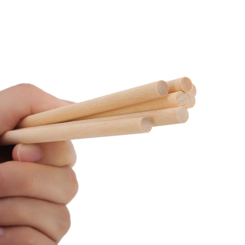 Premium Unfinished Natural Wood Dowel Rods 100 Pack Of Six By One Quarter Inch Smooth Cylinders held in hand for arts and crafts.