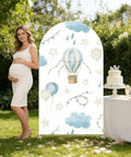 Spandex Arch Backdrop Cover For Baby Birthday And Baby Shower Blue Hot Air Balloon Theme Wrinkle-Resistant Stretch Polyester Backdrop Easy Setup For Photos 7.2 By 4 Feet set up outdoors with cake table and pregnant woman.