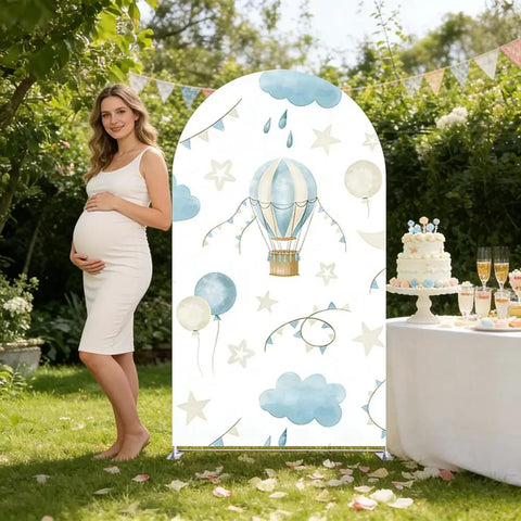Spandex Arch Backdrop Cover For Baby Birthday And Baby Shower Blue Hot Air Balloon Theme Wrinkle-Resistant Stretch Polyester Backdrop Easy Setup For Photos 7.2 By 4 Feet set up outdoors with cake table and pregnant woman.