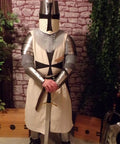 Medieval knight wearing iron gorget and spaulders armor set standing indoors