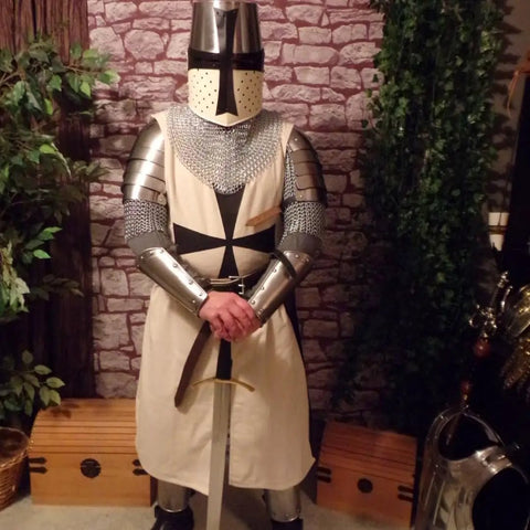 Medieval knight wearing iron gorget and spaulders armor set standing indoors
