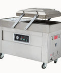 Heavy Duty Double Chamber Vacuum Sealer with stainless steel housing and open lid for sealing meat and seafood.