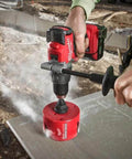Milwaukee 4-1/4 in Big Hawg carbide hole saw, red, mounted on a drill at outdoor construction site, front view.