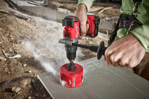 Milwaukee 4-1/4 in Big Hawg carbide hole saw, red, mounted on a drill at outdoor construction site, front view.