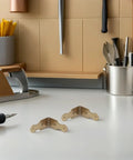 Close-up of two Six Pack L Shaped Brass Corner Protectors For Jewelry Boxes And Gift Boxes on a kitchen counter