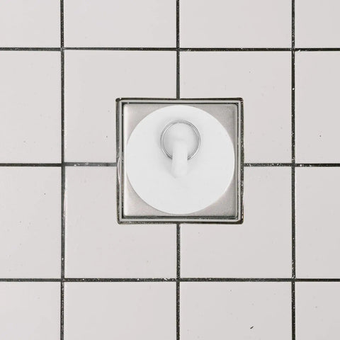 Rubber Bath Tub Drain Stoppers 4pcs with Pull Ring for Basins, white rubber plug installed in a shower drain.