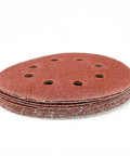 Premium 5 Inch Hook Loop Sanding Discs Featuring Eight Holes For Quick Dust Extraction And Killer Grip For Smooth As Butter Wood Metal Finishing The Real Deal Aluminum Oxide Abrasive Pads stacked in a pile.