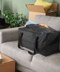 Mid-Size Weekender Travel Duffle Bag, 24x12x12 Inch, 53L Capacity sitting on grey couch, showcasing spacious main compartment