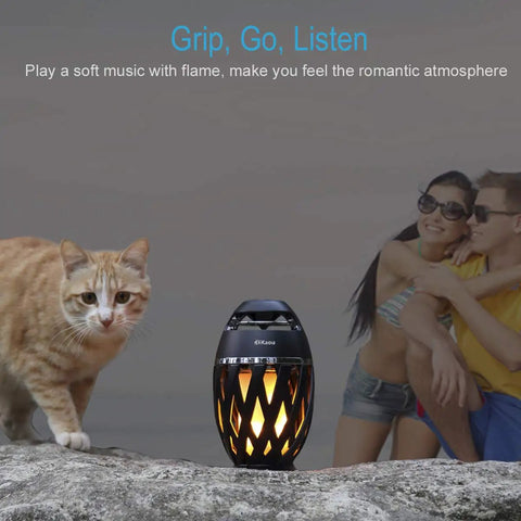 LED Flame Outdoor Table Lamp With Bluetooth Speaker Rechargeable Ambience Lantern beside a cat and couple outdoors.