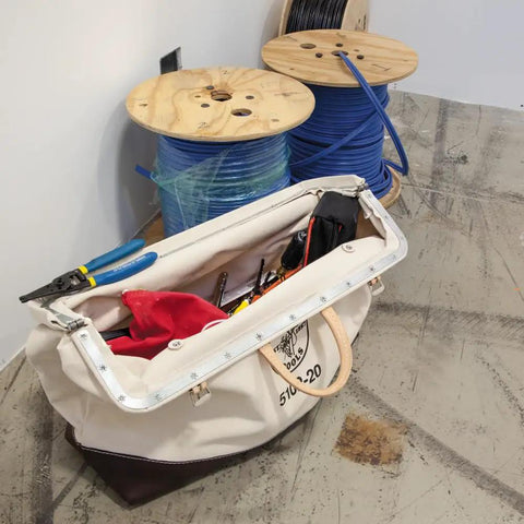 Heavy Duty Natural Canvas Tool Bag With Wide Hinged Opening, Leather Handles, Riveted Construction next to spools.