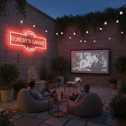Outdoor scene with Custom Garage Neon Sign With Handmade Personalization Dimmable LED Wall Light For Home Workshop Carport Or Man Cave Perfect Gift For Dad Birthday Christmas 3D Art Look And Eye Catching Glow illuminating patio area, projecting onto a wall.