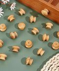 Pack Of Fifty Unfinished Wood Drawer Knobs In Classic Mushroom Shape One Inch Cabinet Handles arranged on a green surface.