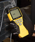 Person using Versatile On The Go Cable Tester Kit with Scout Pro 3 for testing connections on a equipment panel.