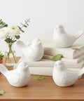 Four Pack White Ceramic Bird Toilet Bolt Caps Super Chic Animal Flange Covers Hella Durable And Totally Waterproof For Quick Bathroom Upgrades With Great Decor Vibes All Year Long on stacked books.