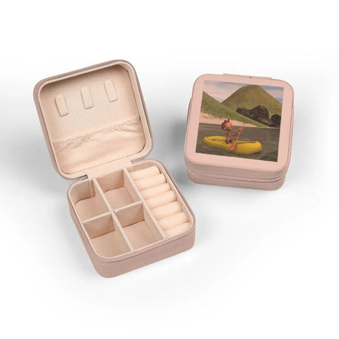 Open pink jewelry case with plush lining and compartments, featuring a lid image of Pink Cartoon Man On Ocean Rowing Inflatable Raft.