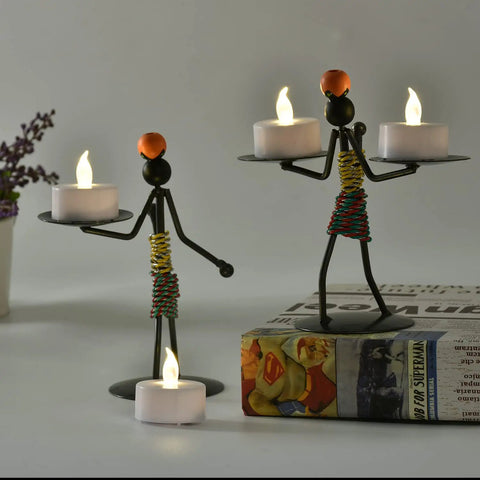 Two metallic figurines holding 100 Count Battery Powered LED Tea Lights Flameless Flickering Warm White Candles Long Lasting CR2032