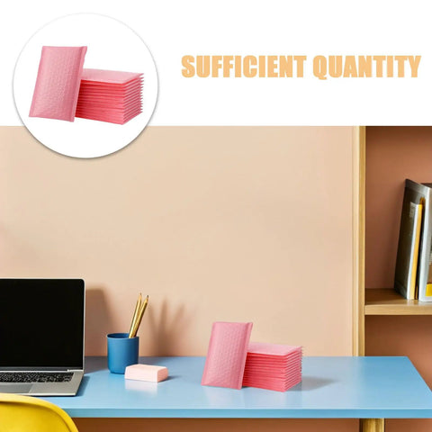 Stack of pink bubble padded mailers self seal envelopes 100 pack for jewelry and makeup supplies on a desk setup