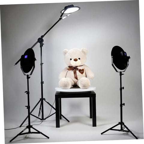 Stunning White Motorized Rotating Display Stand With Mirror Finish Turntable For Jewelry Watches Digital Gadgets And Collectibles 5Kg Capacity Smooth Spinning Showcase For Photography Retail Stores with light setup and teddy bear.