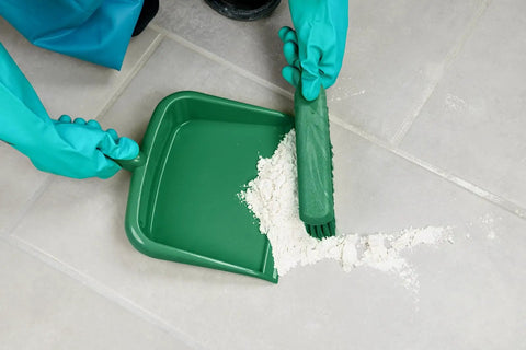 Gloved hands using a large handheld dustpan with wide lip and hanging hole, 10 inch green durable polypropylene, collecting debris