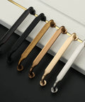 Set of metal cabinet handles in various finishes, including oil rubbed bronze, displayed on a black and white surface.